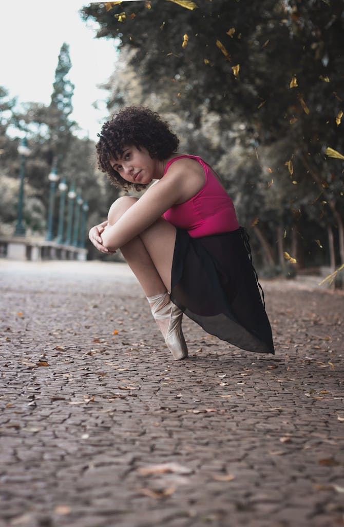 Elegant ballet dancer in urban park setting showcasing flexible pose on cobblestone path.